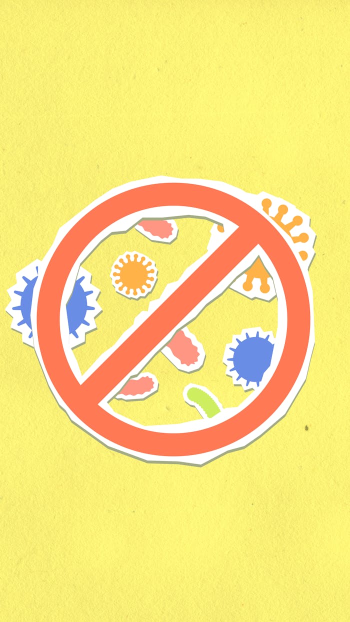 Overhead view of decorative cardboard appliques of prohibition symbol on different viruses and microbes on yellow background